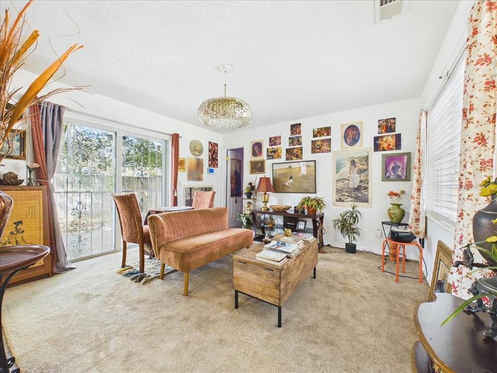 A living room features a velvet settee, a wooden coffee table, and a gallery wall — 3314 NW 45TH AVENUE, GAINESVILLE, FL