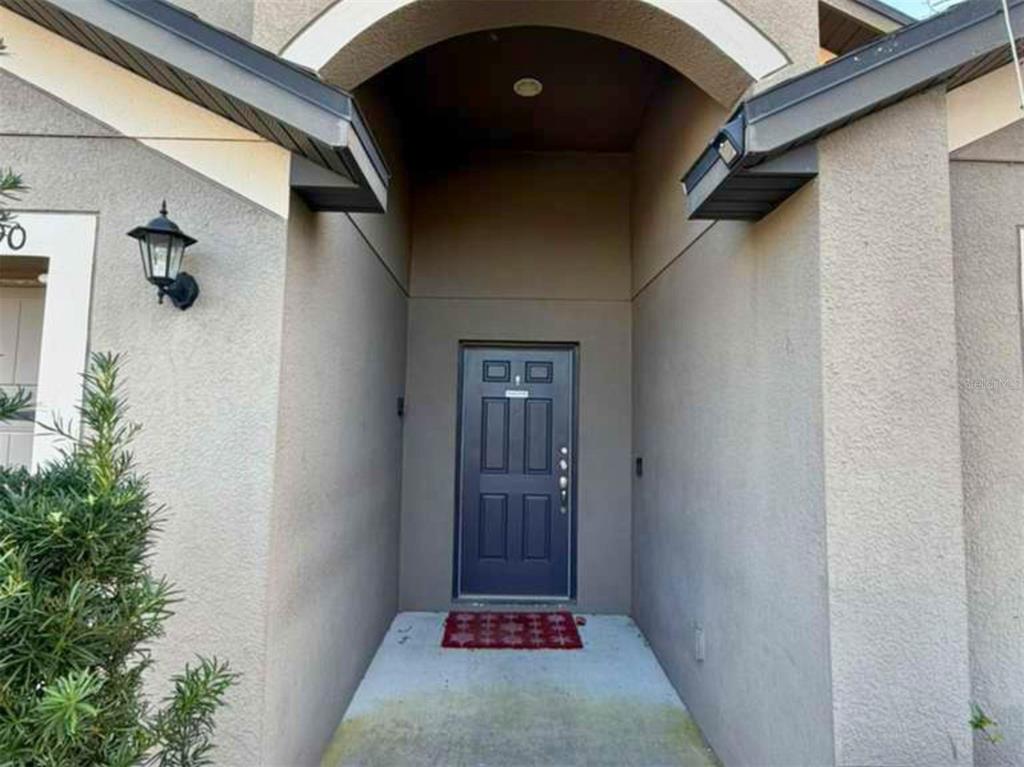 The exterior view shows a recessed front entryway with a dark door and a lantern — 1090 WOODLARK DRIVE, HAINES CITY, FL