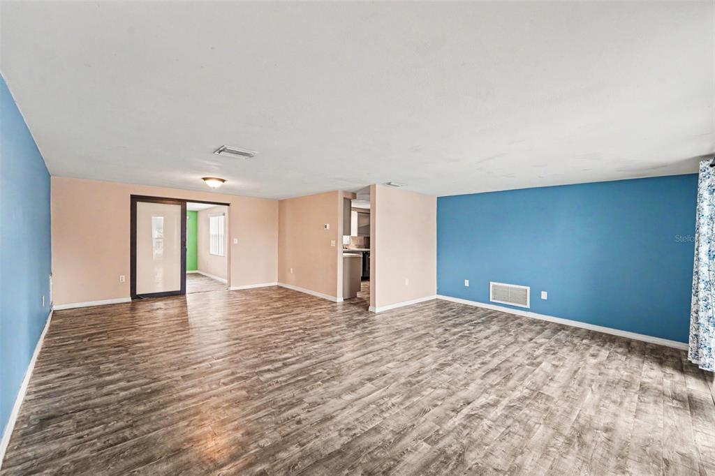 An open living area features wood-look flooring, blue and beige walls, and a sliding door — 7923 IRONBARK DRIVE, PORT RICHEY, FL