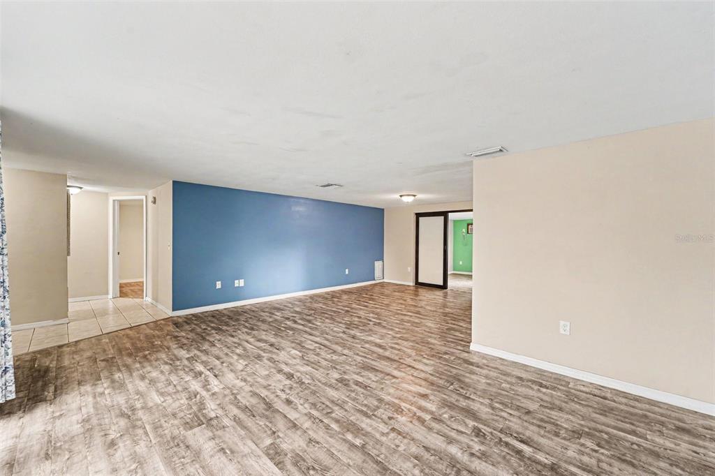 A living room features a green accent wall, a glass coffee table, and wood-look flooring — 7923 IRONBARK DRIVE, PORT RICHEY, FL