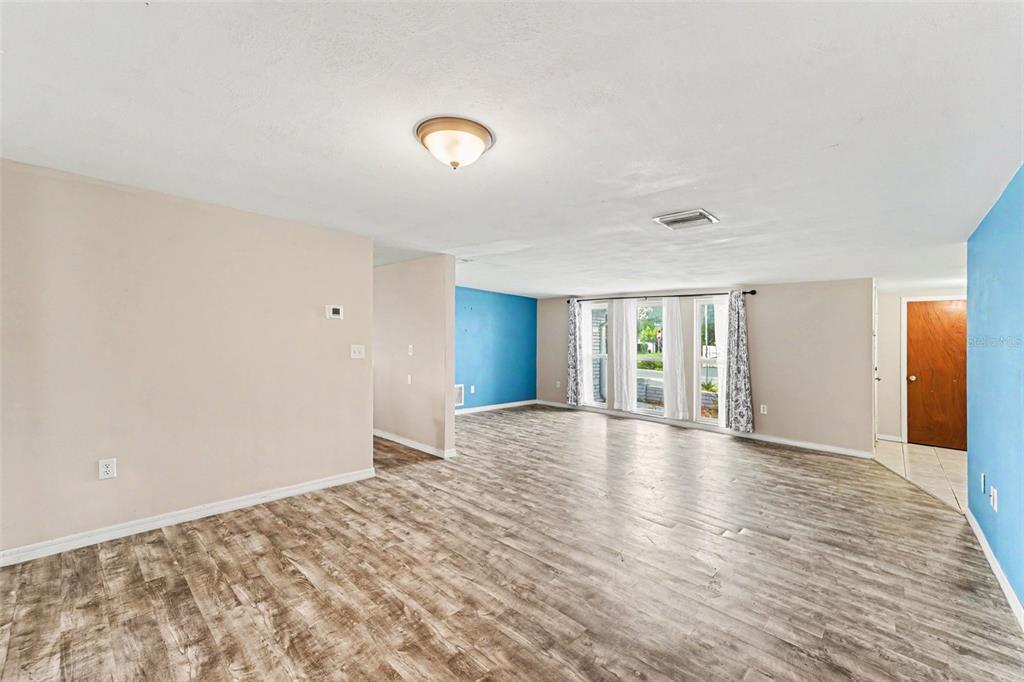 A room with wood-look flooring, a green accent wall, a window, and a glass-paneled door — 7923 IRONBARK DRIVE, PORT RICHEY, FL