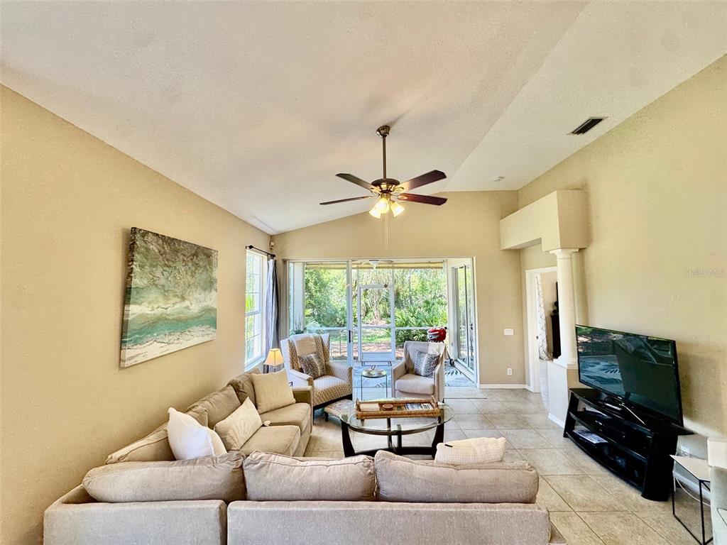 A living room features a sectional sofa, a television, and a ceiling fan under vaulted ceilings — 7330 KENSINGTON COURT, BRADENTON, FL