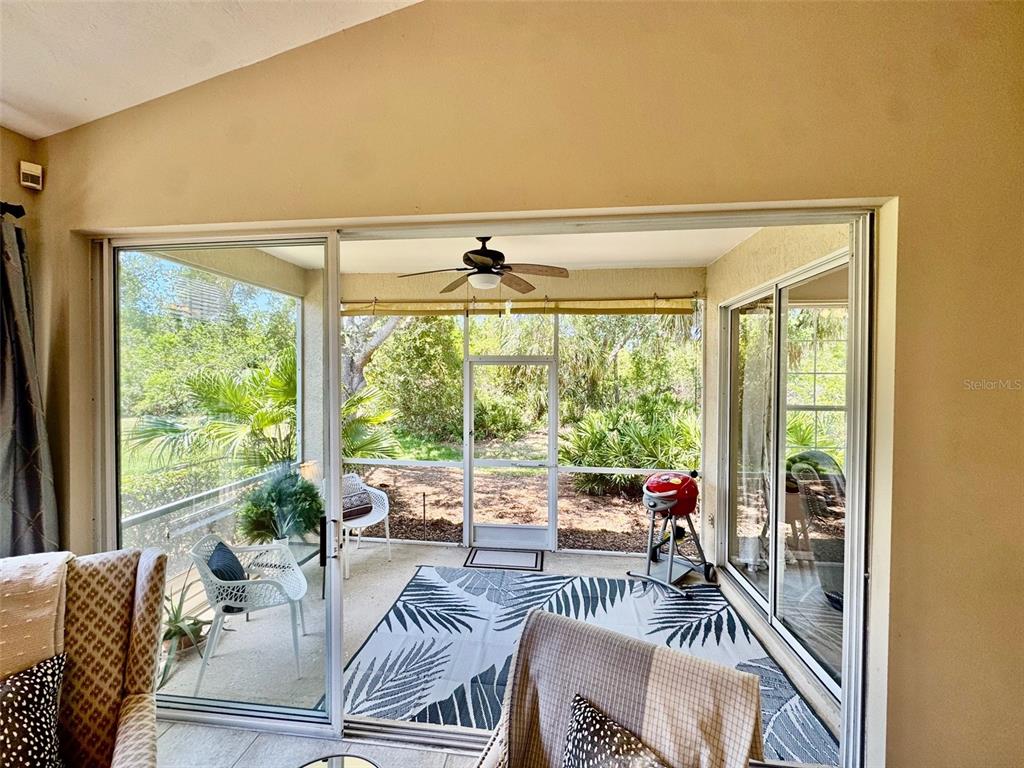 A sunroom with sliding glass doors, a ceiling fan, and a view of outdoor greenery — 7330 KENSINGTON COURT, BRADENTON, FL
