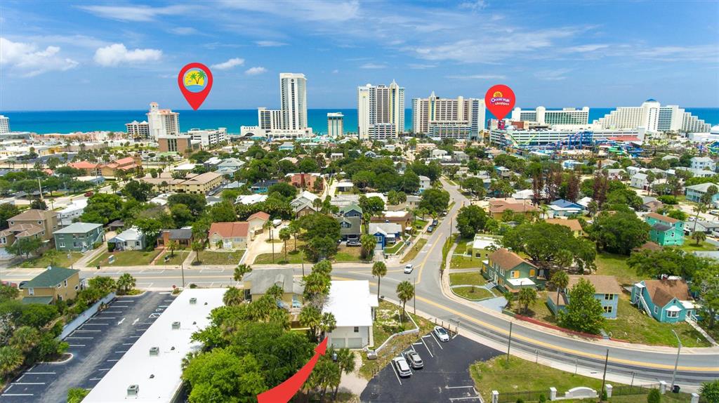 An aerial view shows a coastal city with a white building highlighted by a red arrow — 419 N PENINSULA DRIVE, DAYTONA BEACH, FL