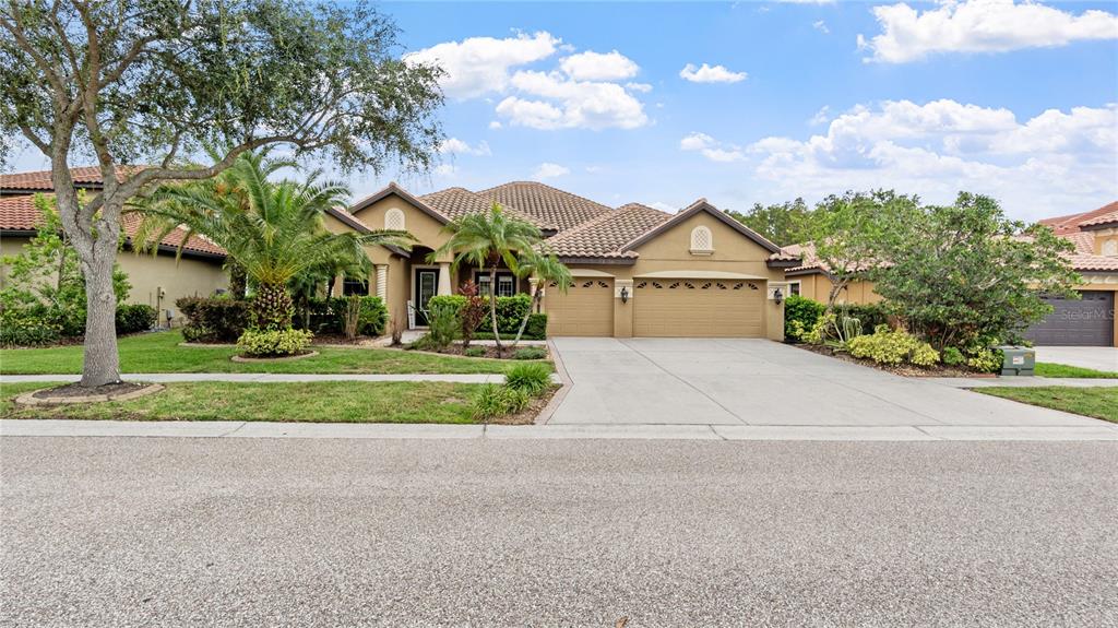 A single-story house with a tile roof, three-car garage, and landscaped front yard — 20023 PERGOLA BEND LANE, TAMPA, FL
