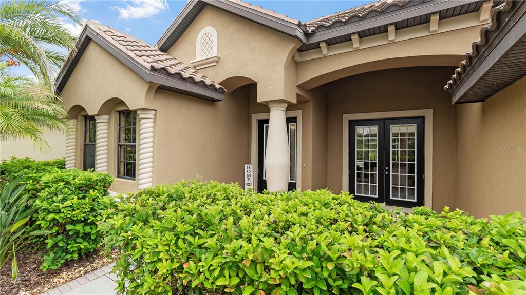 The exterior of a tan stucco house features a covered entryway with a central pillar — 20023 PERGOLA BEND LANE, TAMPA, FL