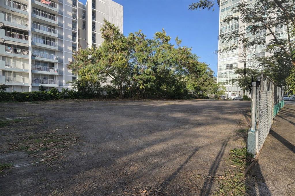 A flat, vacant dirt lot sits between two tall apartment buildings under a clear sky — 836 CALLE AÑASCO, SAN JUAN, PR