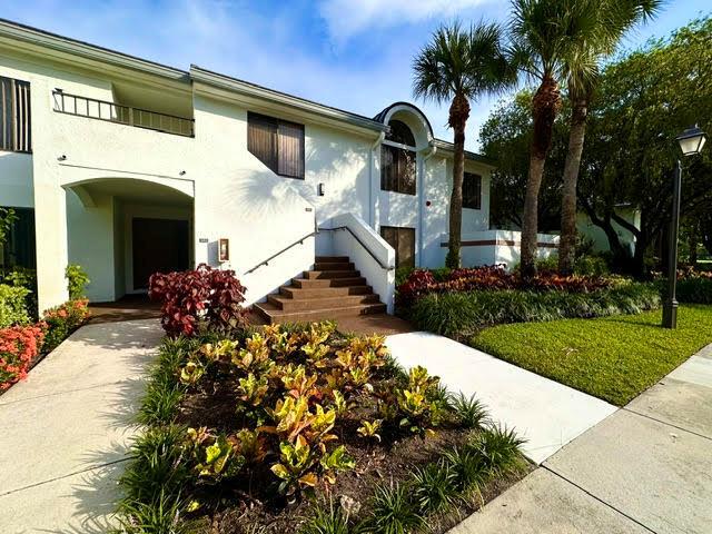 A two-story white building features a concrete staircase leading to an arched entryway — 7344 Clunie Place # 13605, Delray Beach FL 33446, DELRAY BEACH, FL