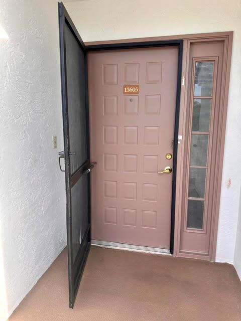 A tan front door with a screen door and a side window on a porch — 7344 Clunie Place # 13605, Delray Beach FL 33446, DELRAY BEACH, FL
