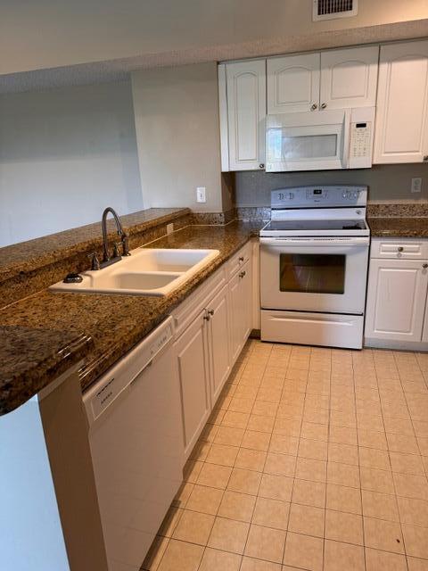 A kitchen features white cabinets, granite countertops, a double sink, and white appliances — 272 Village Boulevard Unit 7305, Tequesta FL 33469, TEQUESTA, FL