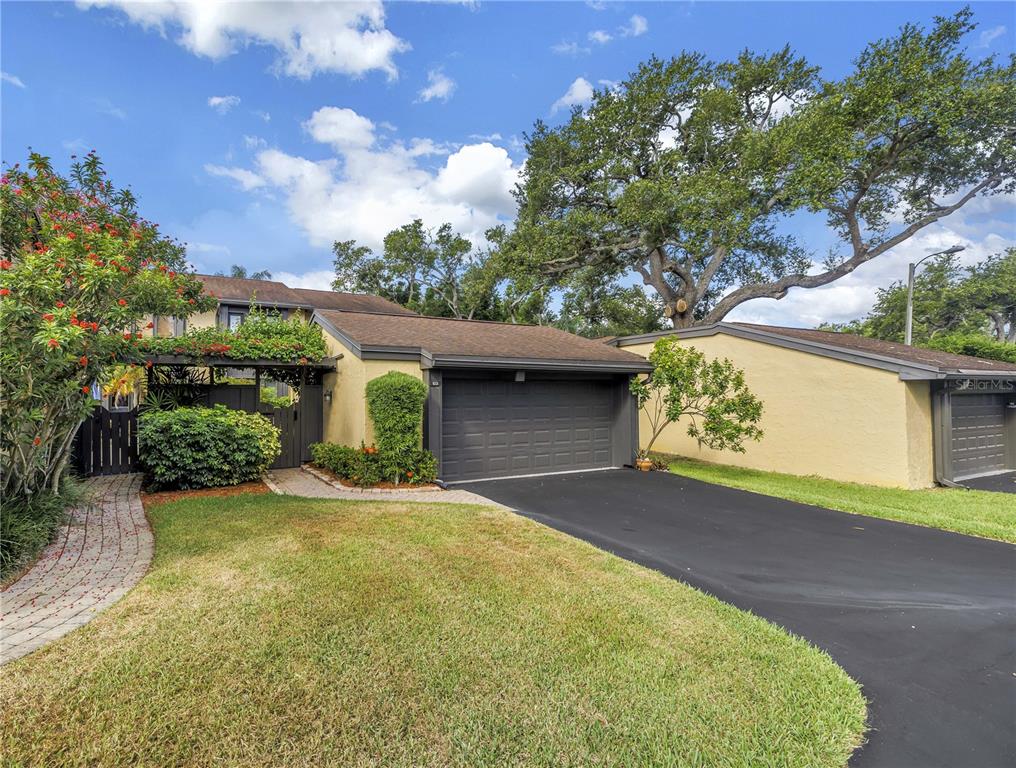 A single-story house with a dark garage door, a paved driveway, and a brick walkway — 13300 INDIAN ROCKS ROAD UNIT 103, LARGO, FL