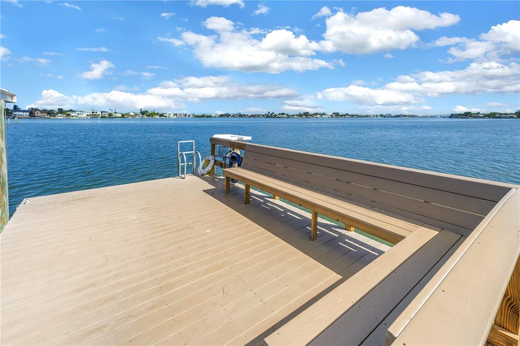 A wooden dock with built-in bench seating overlooks a wide body of water — 13300 INDIAN ROCKS ROAD UNIT 103, LARGO, FL