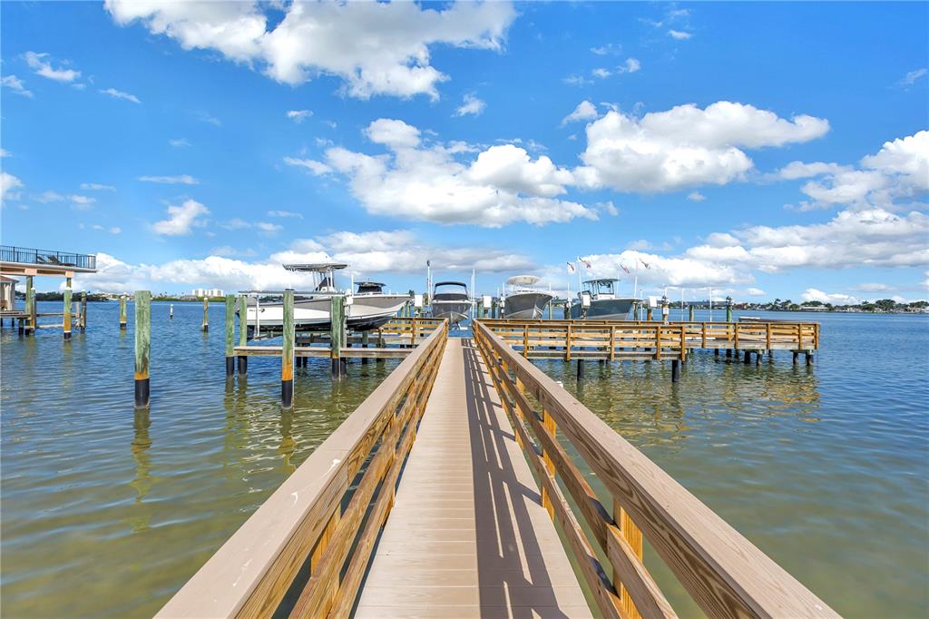 A wooden pier extends over calm water toward several boats docked at a marina — 13300 INDIAN ROCKS ROAD UNIT 103, LARGO, FL
