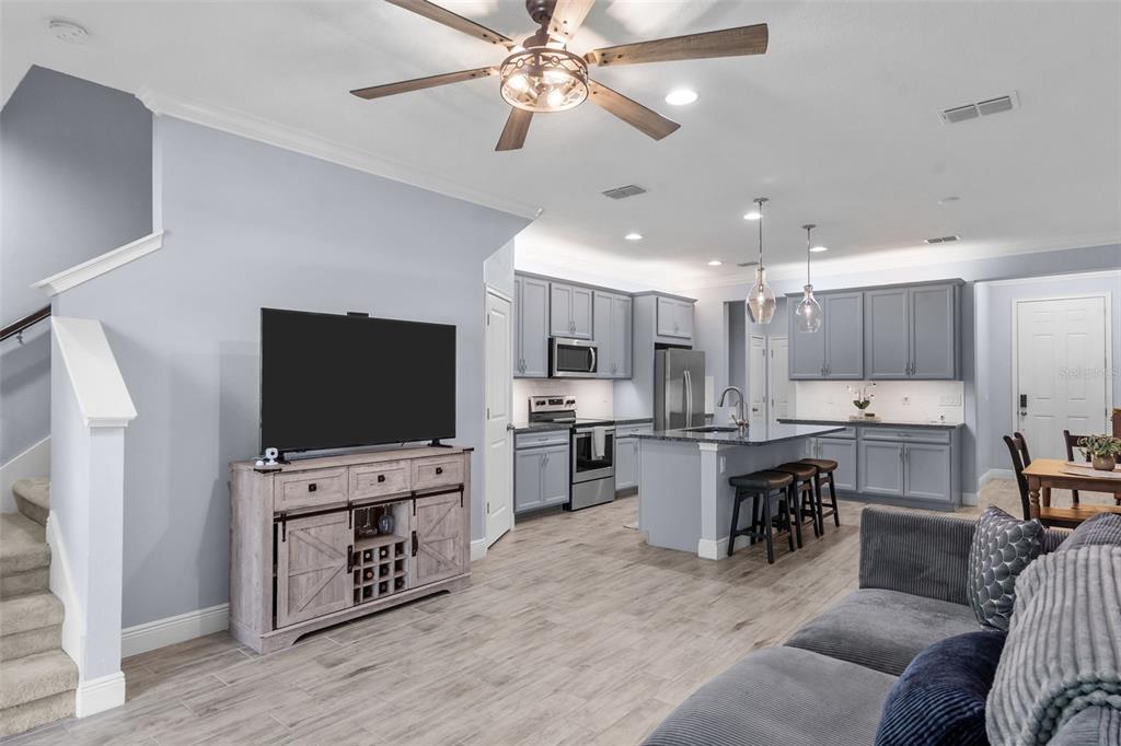 An open-concept living room and kitchen with gray cabinetry, a kitchen island, and wood-look flooring — 14221 PONDHAWK LANE, TAMPA, FL