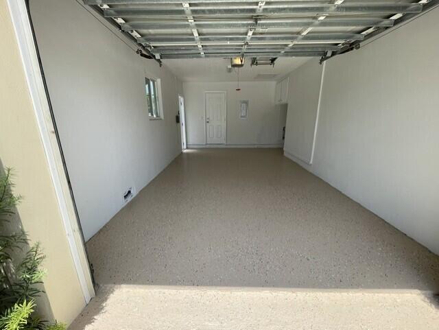 A garage with white walls, a white door, and a speckled epoxy floor finish — 180 SW 77th Avenue, Margate FL 33068, MARGATE, FL