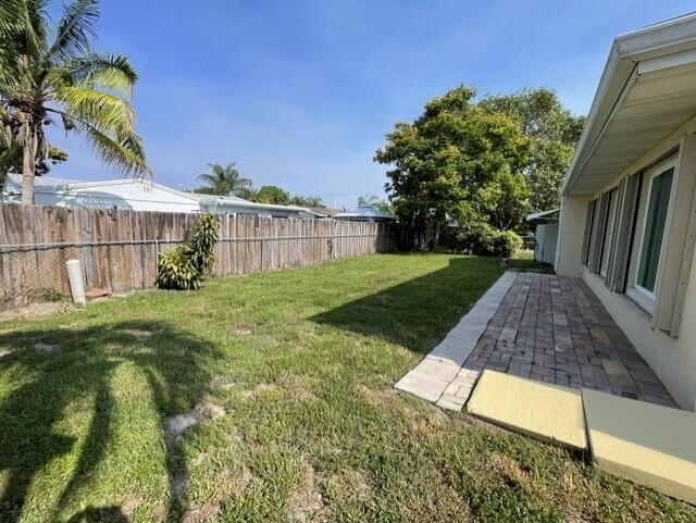 A beige house exterior features a paved patio area and three large sliding glass windows — 180 SW 77th Avenue, Margate FL 33068, MARGATE, FL