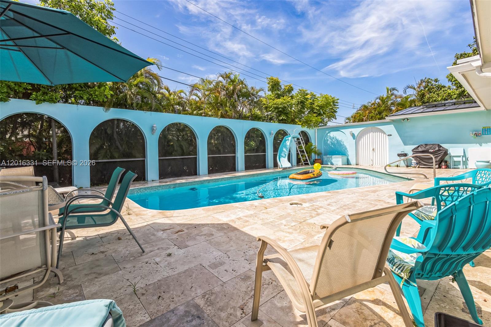 A backyard swimming pool features a slide, patio furniture, and a light blue arched wall — 633 N Crescent Dr, Hollywood FL 33021, HOLLYWOOD, FL
