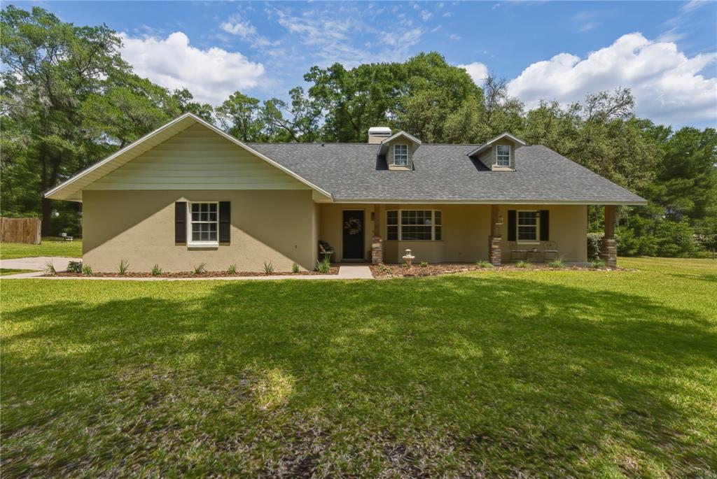 A single-story house with a tan stucco exterior, dark shutters, and two roof dormers — 26 COUNT FLEET DRIVE, OCALA, FL