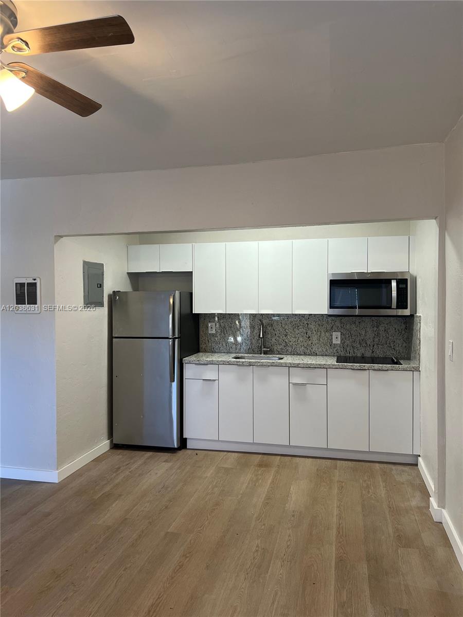 A kitchen features white cabinets, stainless steel appliances, and granite countertops over wood-look flooring — 361 Sharar Ave # 6, Opa-Locka FL 33054, OPA-LOCKA, FL