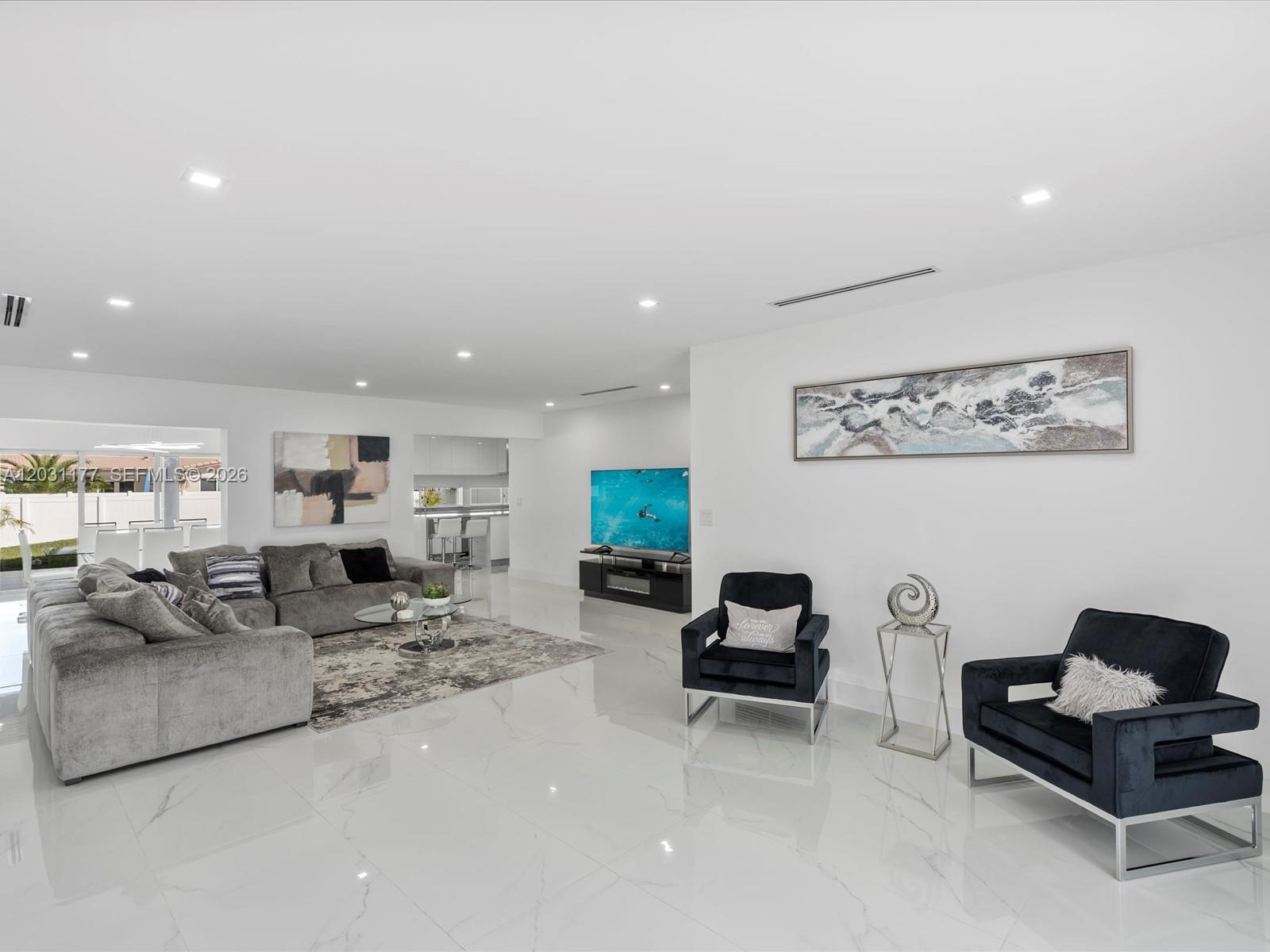 A bright, open-concept living room features white marble floors, a grey sectional, and two armchairs — 4901 Grant St, Hollywood FL 33021, HOLLYWOOD, FL