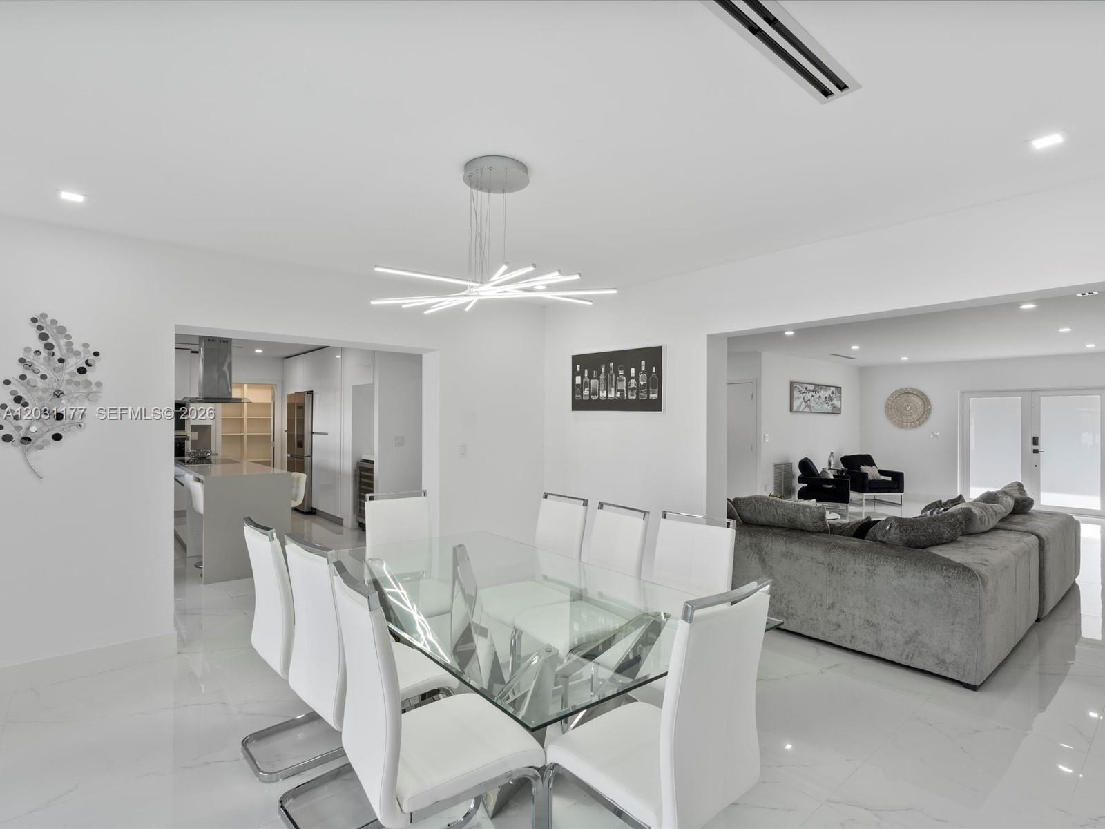 A modern dining room features a glass table, white chairs, and a contemporary light fixture — 4901 Grant St, Hollywood FL 33021, HOLLYWOOD, FL
