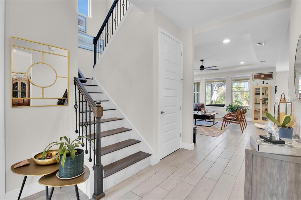 An entryway features a staircase with dark wood treads, a white door, and tiled flooring — 8768 SONOMA COAST DRIVE, WINTER GARDEN, FL