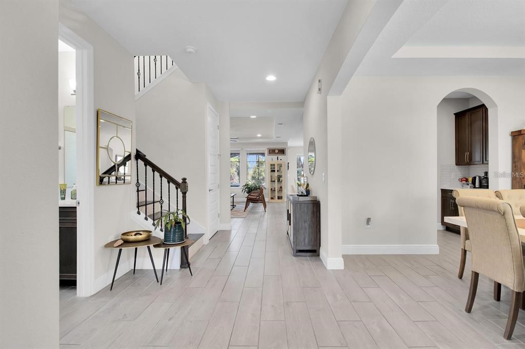 A bright entryway features light tile flooring, a staircase with dark railings, and an open layout — 8768 SONOMA COAST DRIVE, WINTER GARDEN, FL