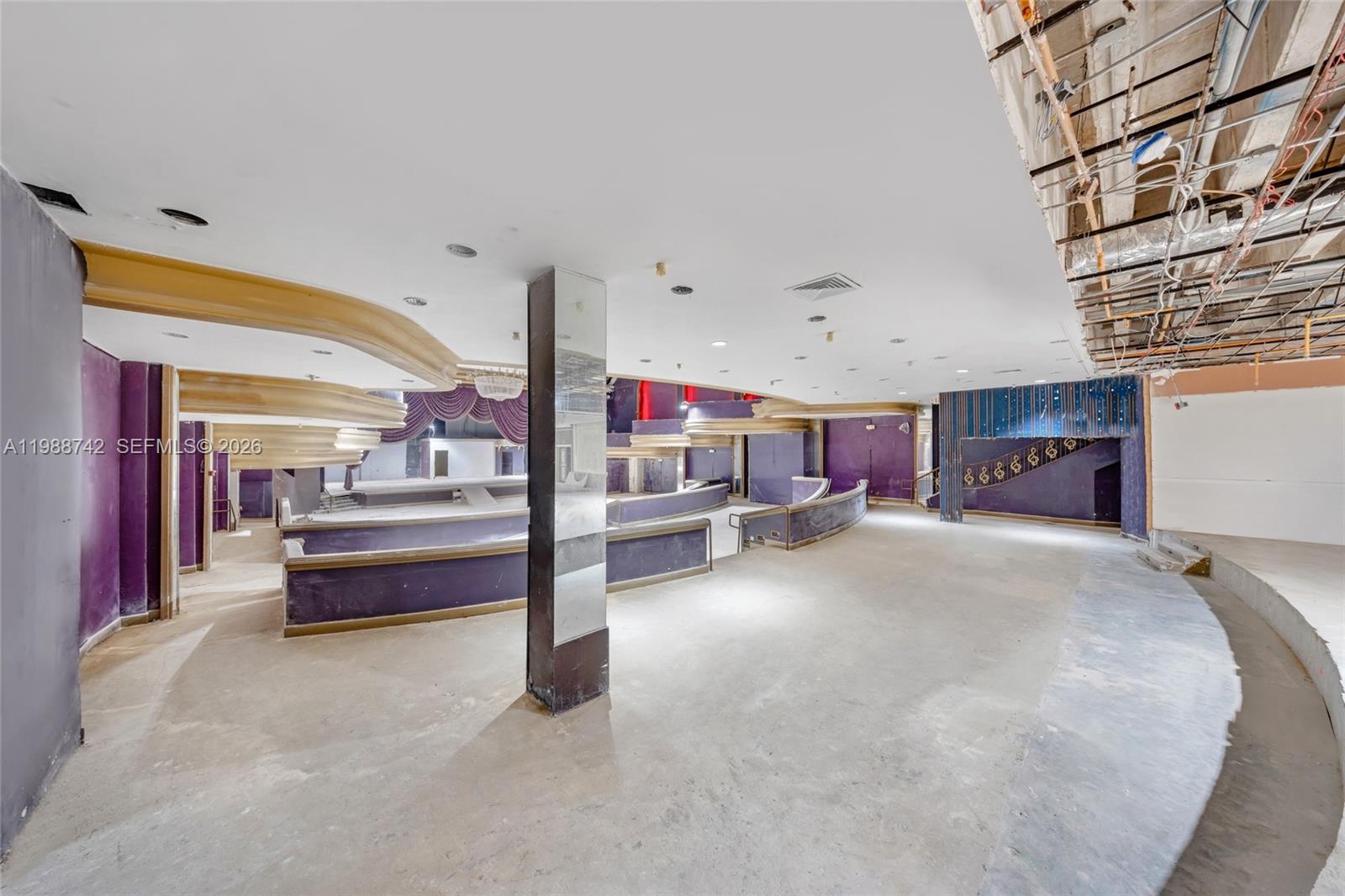 An unfinished, multi-level commercial space features purple walls, tiered platforms, and exposed ceiling infrastructure — 5445 Collins Ave, Miami Beach FL 33140, MIAMI BEACH, FL