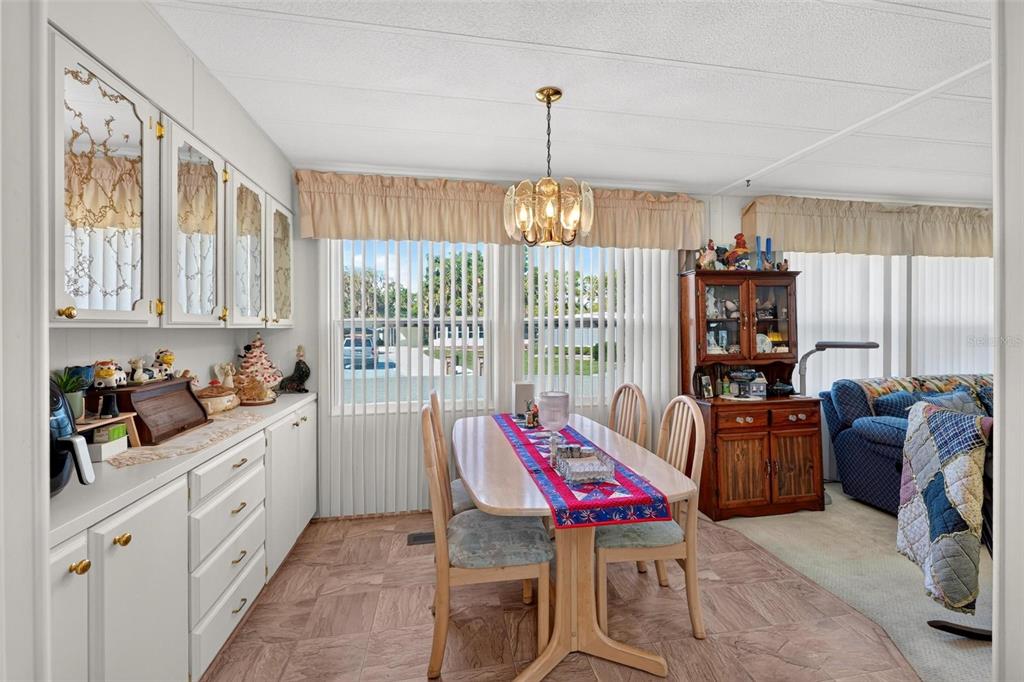 A dining area with a wooden table, chairs, white cabinetry, and a hanging light fixture — 141 AZALEA TRAIL, LEESBURG, FL