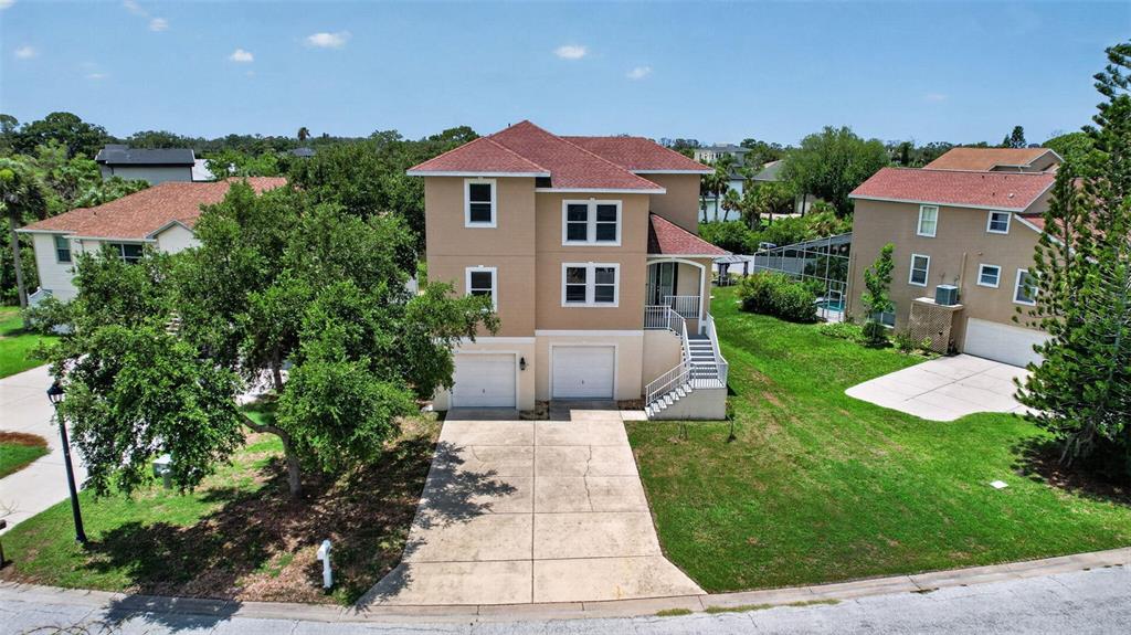 An aerial view shows a two-story tan house with a red roof and two garages — 7327 BRIGHTWATERS COURT, NEW PORT RICHEY, FL