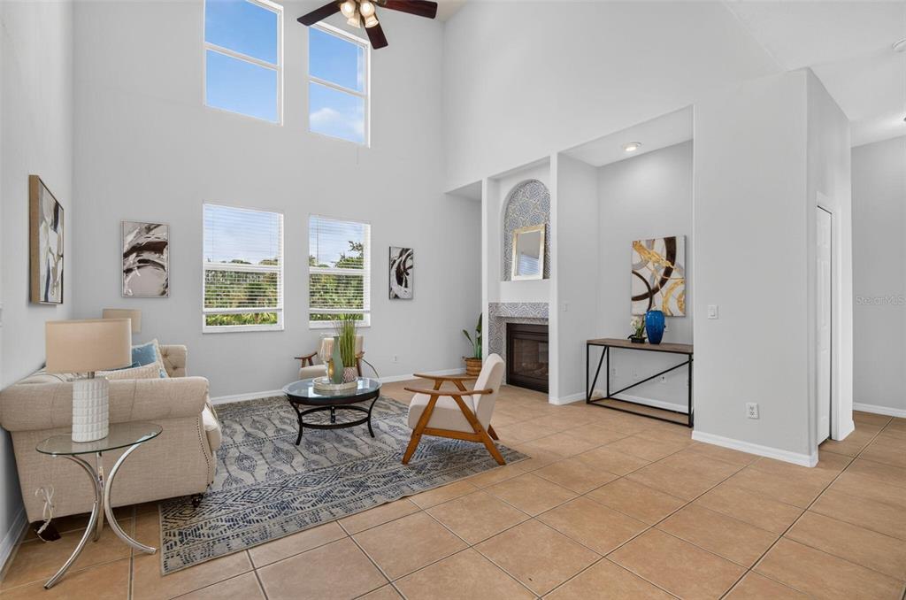 A living room features high ceilings, tile flooring, a fireplace, and large windows — 7327 BRIGHTWATERS COURT, NEW PORT RICHEY, FL