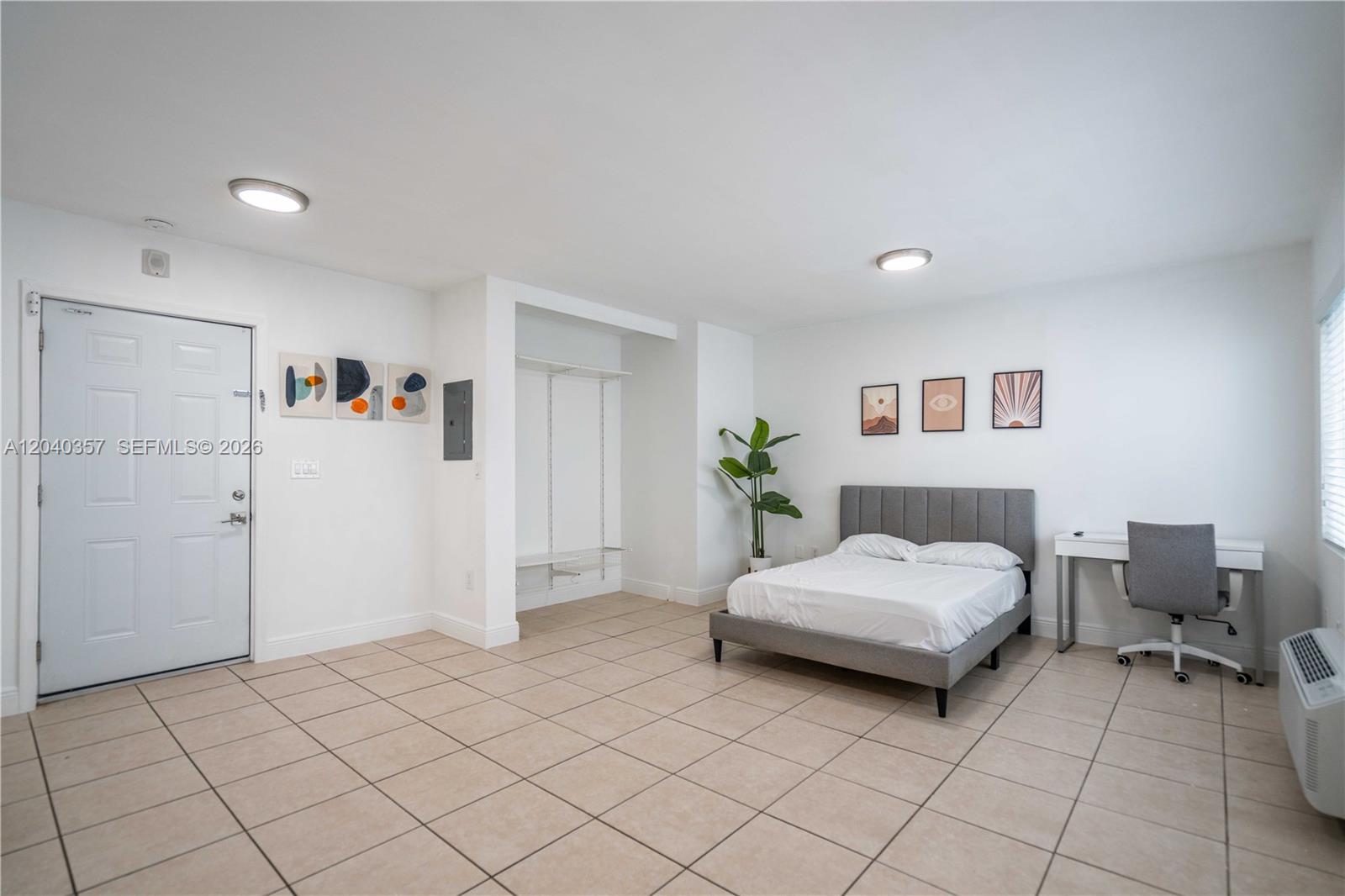 A bedroom with tile flooring, a bed, a desk, and an open closet area — 6971 Carlyle Ave # 107, Miami Beach FL 33141, MIAMI BEACH, FL