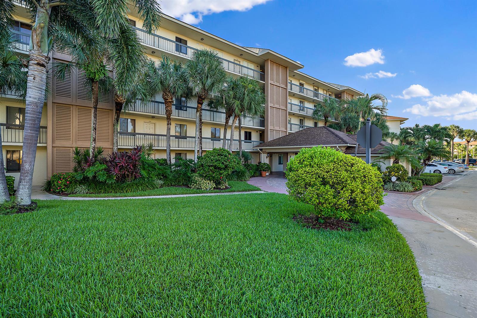 A multi-story apartment building with balconies, palm trees, and a landscaped lawn in front — 2601 Marina Isle Way # 402, Jupiter FL 33477, JUPITER, FL