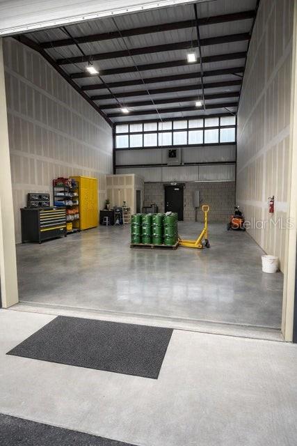 A spacious warehouse interior features a concrete floor, metal ceiling, and a pallet of drums — 2835 HAMMOND ROAD, FORT PIERCE, FL