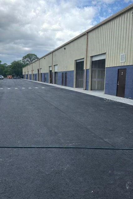 An exterior view of a long industrial warehouse building with multiple roll-up bay doors — 2835 HAMMOND ROAD, FORT PIERCE, FL