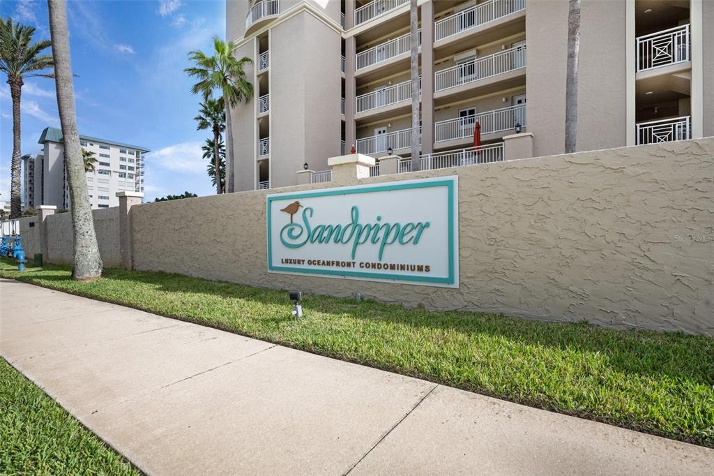A sign for Sandpiper Luxury Oceanfront Condominiums stands in front of a multi-story residential building — 5501 S ATLANTIC AVENUE UNIT 306, NEW SMYRNA BEACH, FL