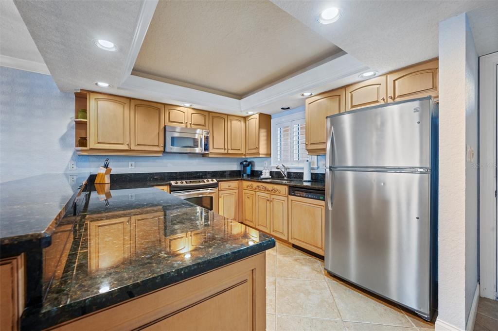 A kitchen with light wood cabinets, dark granite countertops, and stainless steel appliances — 5501 S ATLANTIC AVENUE UNIT 306, NEW SMYRNA BEACH, FL