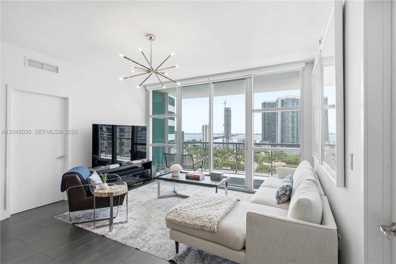 A modern living room features a white sectional sofa, dark armchair, and floor-to-ceiling windows — 3301 NE 1st Ave # H1704, Miami FL 33137, MIAMI, FL