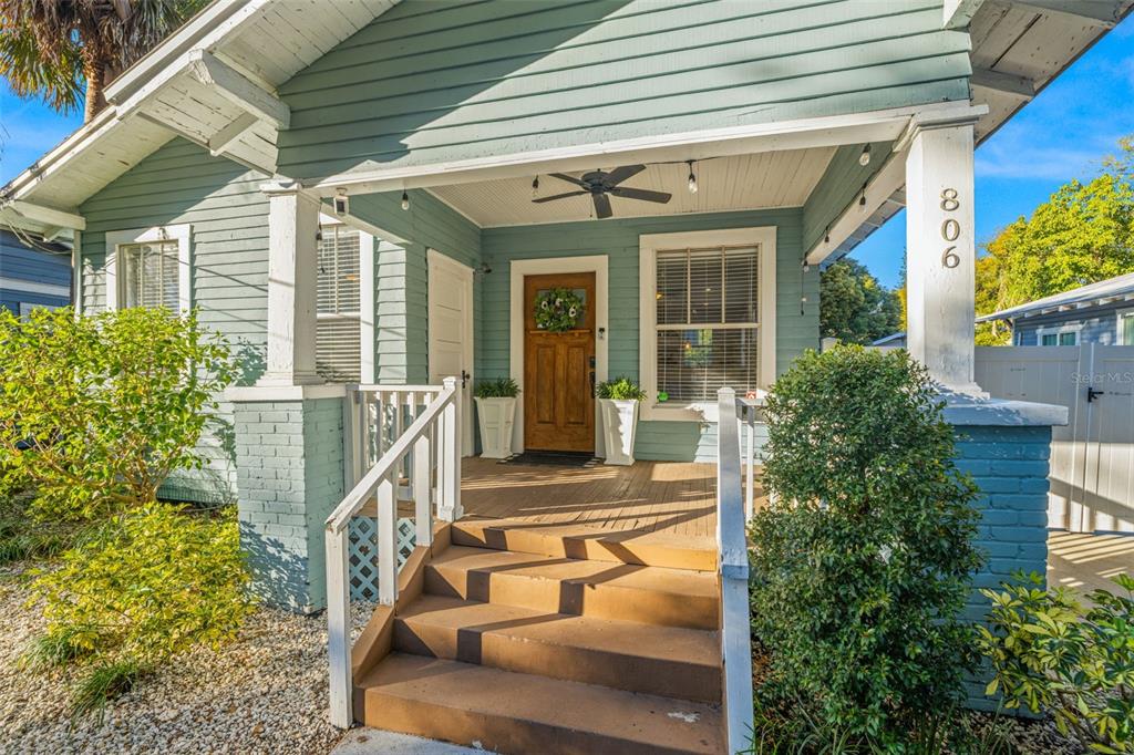 A light blue bungalow features a covered front porch with wooden steps and a door — 806 E GENESEE STREET, TAMPA, FL