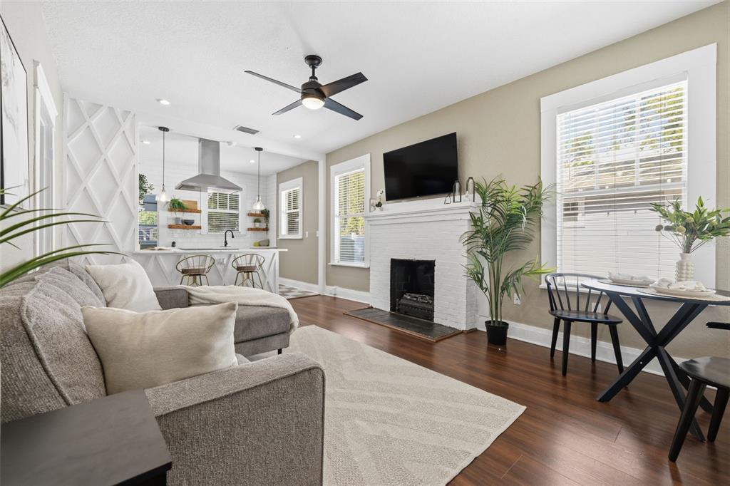 A living room with a white brick fireplace, gray sectional sofa, and an open kitchen — 806 E GENESEE STREET, TAMPA, FL