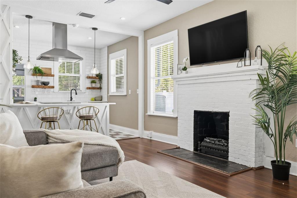 A living room with a white brick fireplace and TV opens into a modern kitchen — 806 E GENESEE STREET, TAMPA, FL