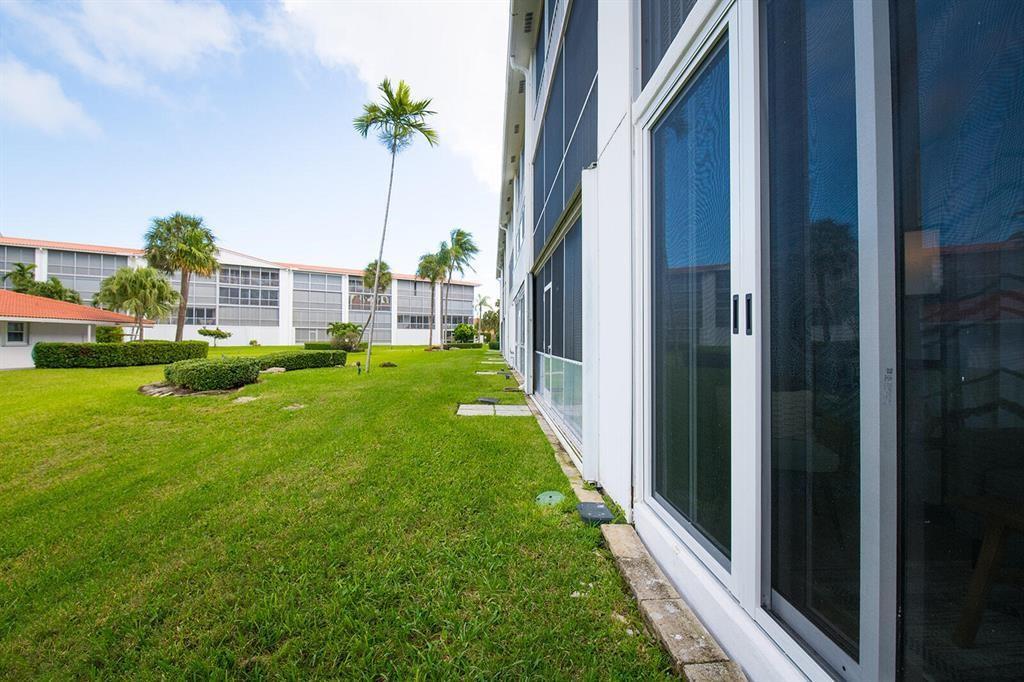 A white exterior walkway features two glass-paneled doors with unit number 126 and welcome mats — 101 NE 19th Avenue # 126, Deerfield Beach FL 33441, DEERFIELD BEACH, FL