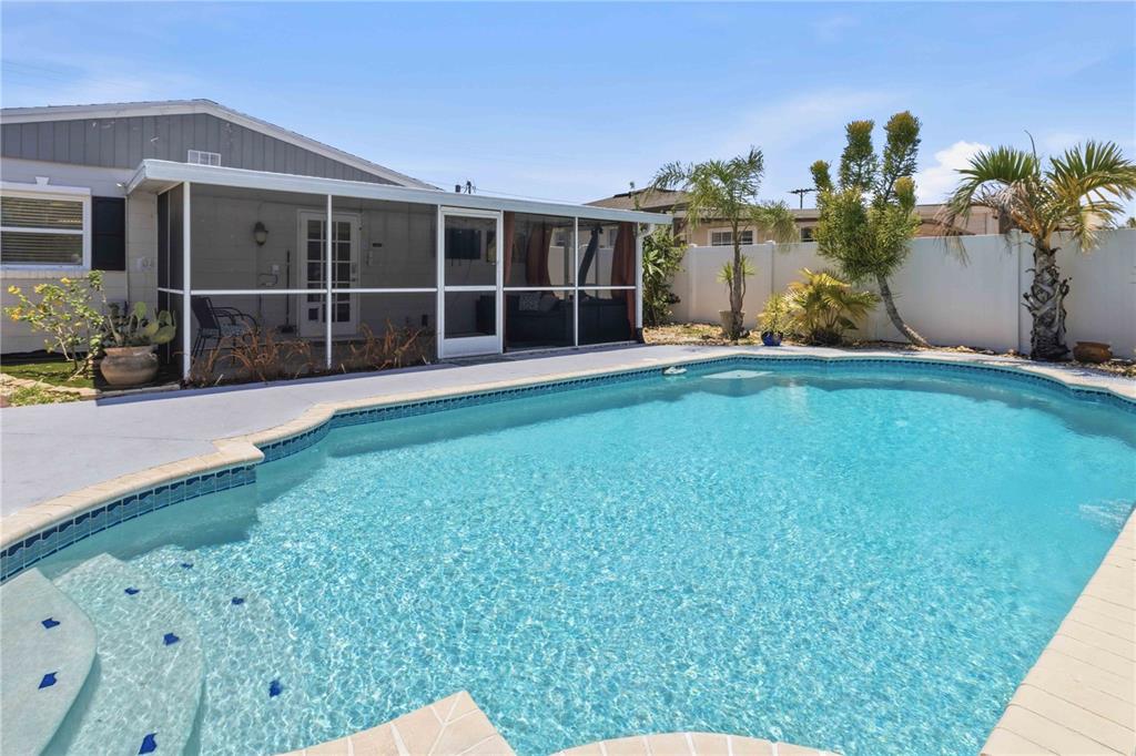 A swimming pool sits in front of a house with a screened-in patio — 2713 W BRADDOCK STREET, TAMPA, FL