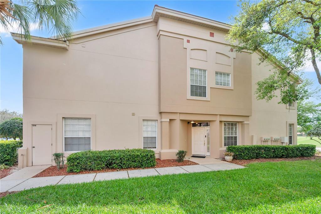 A two-story tan stucco building with a white front door and surrounding landscaping — 427 ENCLAVE PLACE UNIT 427, LAKELAND, FL