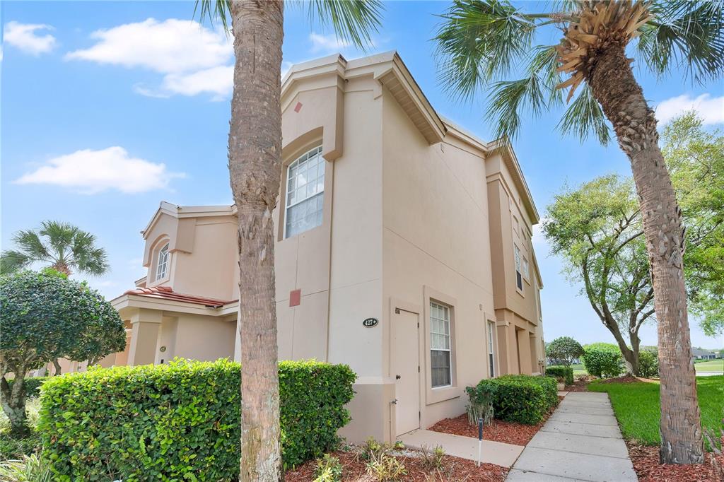 A beige two-story townhouse exterior features a side entrance, palm trees, and a walkway — 427 ENCLAVE PLACE UNIT 427, LAKELAND, FL