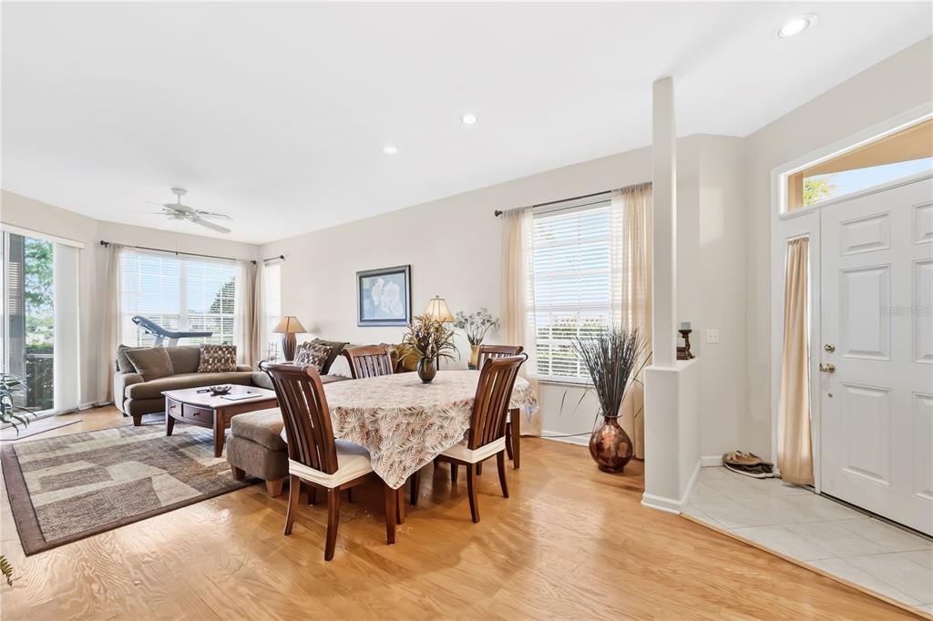 A dining area with a wood table and chairs sits adjacent to a living room — 427 ENCLAVE PLACE UNIT 427, LAKELAND, FL
