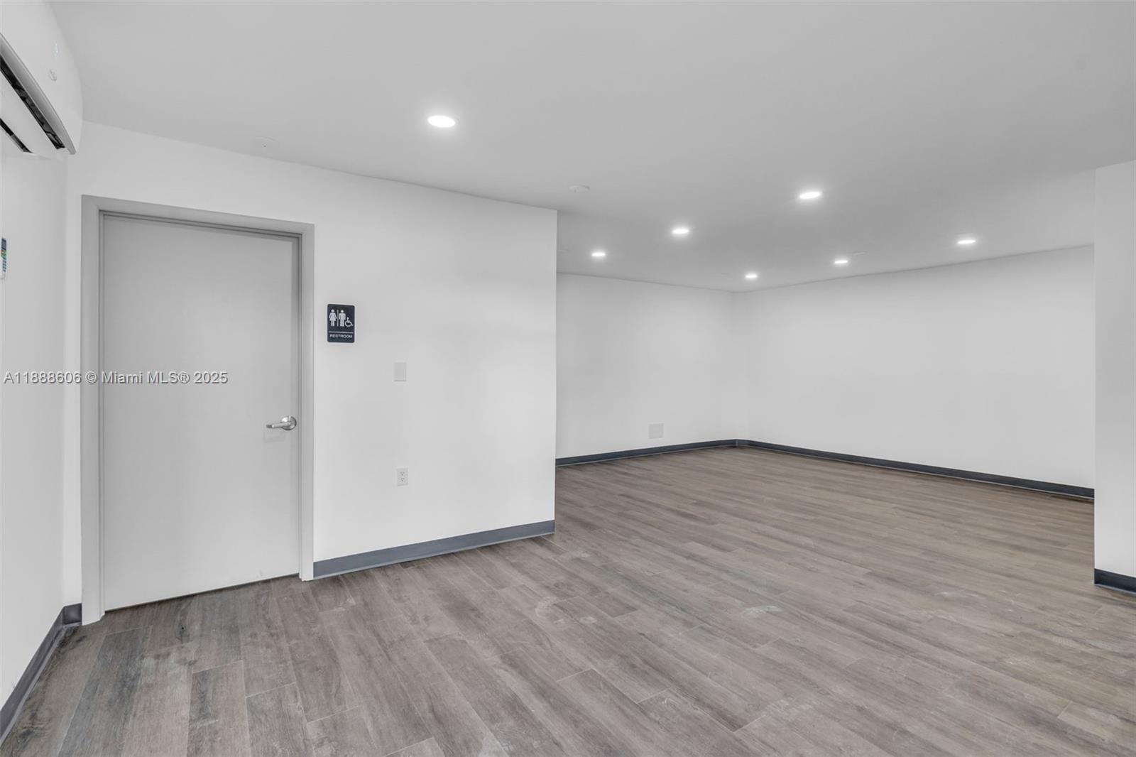 An empty room features white walls, recessed lighting, and gray wood-look flooring — 333 W 75th Pl # 1D, Hialeah FL 33014, HIALEAH, FL
