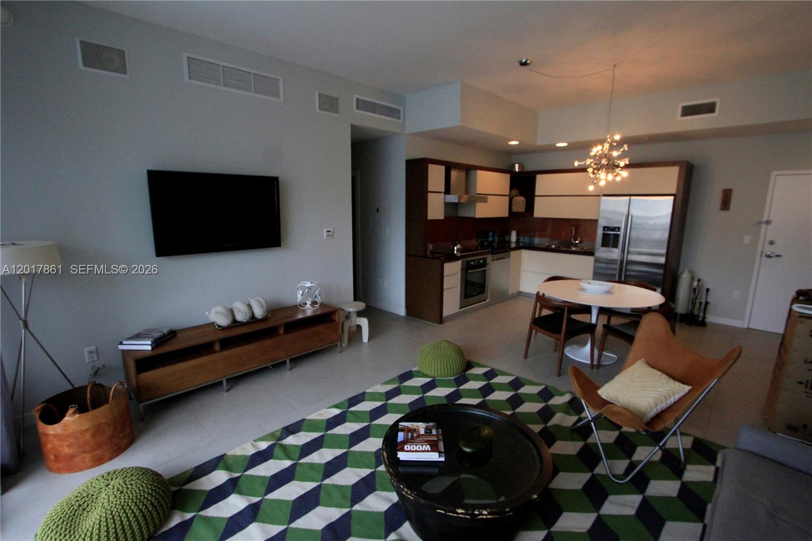 An open-concept living area features a kitchen, dining table, and a geometric-patterned area rug — 2100 Park Ave # 202, Miami Beach FL 33139, MIAMI BEACH, FL