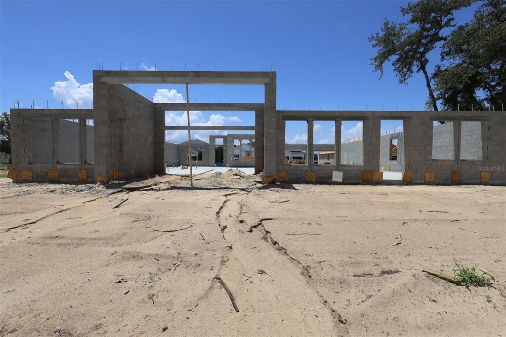 An unfinished room with exposed wooden wall studs, roof trusses, and a window looking outside — 3722 WOLVES CREEK PLACE, APOPKA, FL