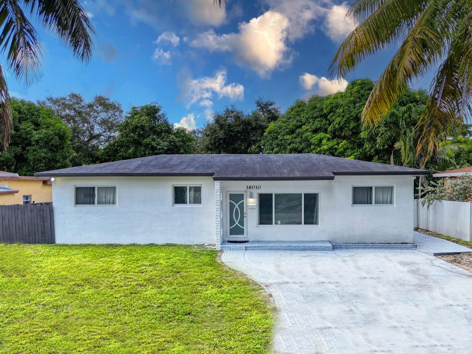 A single-story white house with a flat roof, a front lawn, and a paved driveway — 16010 NE 5th Avenue, Miami FL 33162, MIAMI, FL